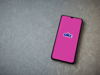 Lod, Israel - 8 Temmuz 2020: OkCupid uygulama ekranı seramik taş zemin üzerinde siyah bir cep telefonunun logosu var. Üst görünüm düzlüğü kopyalama alanı ile yatıyordu.