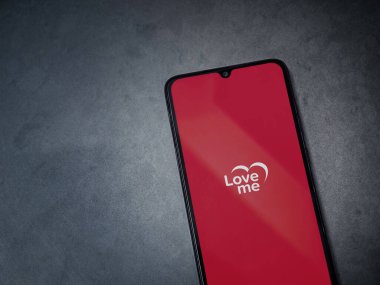 Lod, Israel - 8 Temmuz 2020: Loveme uygulama başlatma ekranı koyu mermer taşlı arka planda siyah bir cep telefonunun logosu. Üst görünüm düzlüğü kopyalama alanı ile yatıyordu.