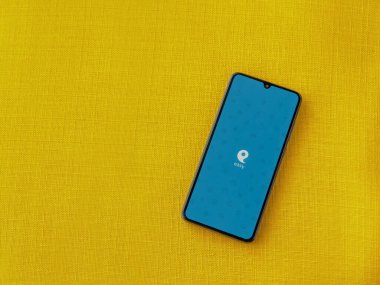 Lod, Israel - 8 Temmuz 2020: Sarı kumaş arka planda siyah bir cep telefonunun logosu olan kolay uygulama başlatma ekranı. Üst görünüm düzlüğü kopyalama alanı ile yatıyordu.