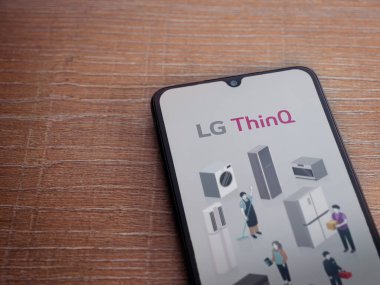 Lod, Israel - 8 Temmuz 2020: LG ThinQ uygulama ekranıyla birlikte ahşap arka planda siyah bir cep telefonu sergilenmektedir. Üst görünüm düzlüğü kopyalama alanı ile yatıyordu.
