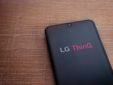 Lod, Israel - 8 Temmuz 2020: LG ThinQ uygulama ekranıyla birlikte ahşap arka planda siyah bir cep telefonu sergilenmektedir. Üst görünüm düzlüğü kopyalama alanı ile yatıyordu.