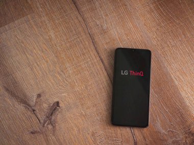 Lod, Israel - 8 Temmuz 2020: LG ThinQ uygulama ekranıyla birlikte ahşap arka planda siyah bir cep telefonu sergilenmektedir. Üst görünüm düzlüğü kopyalama alanı ile yatıyordu.