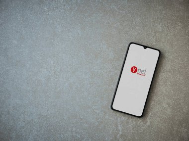 Lod, Israel - 8 Temmuz 2020: ynet uygulama başlatma ekranı seramik taş zemin üzerinde siyah bir cep telefonunun logosu. Üst görünüm düzlüğü kopyalama alanı ile yatıyordu.