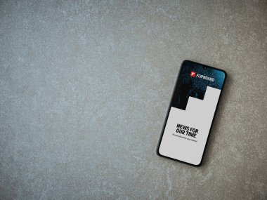 Lod, Israel - 8 Temmuz 2020: Seramik taş zemin üzerinde siyah bir cep telefonunun logosu olan Flipboard uygulaması fırlatma ekranı. Üst görünüm düzlüğü kopyalama alanı ile yatıyordu.