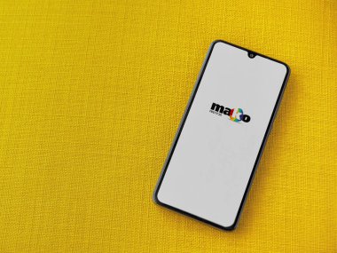 Lod, Israel - 8 Temmuz 2020: Mako uygulama başlatma ekranı üzerinde sarı kumaş arka planda siyah bir cep telefonunun logosu var. Üst görünüm düzlüğü kopyalama alanı ile yatıyordu.