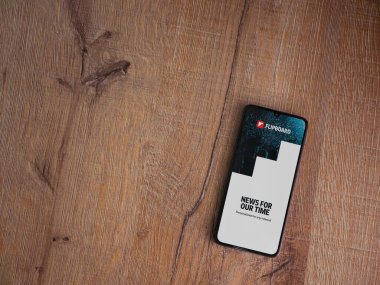 Lod, Israel - 8 Temmuz 2020: Flipboard uygulama başlatma ekranı üzerinde siyah bir cep telefonunun logosu olan ahşap arka planda. Üst görünüm düzlüğü kopyalama alanı ile yatıyordu.