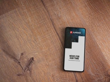Lod, Israel - 8 Temmuz 2020: Flipboard uygulama başlatma ekranı üzerinde siyah bir cep telefonunun logosu olan ahşap arka planda. Üst görünüm düzlüğü kopyalama alanı ile yatıyordu.