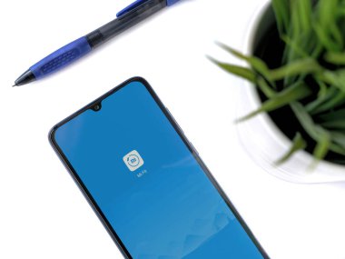 Lod, Israel - 8 Temmuz 2020: Beyaz arka planda logosu olan Mi Fit uygulamalı siyah cep telefonlu modern minimalist ofis çalışma alanı. Üst görünüm düzlüğü kopyalama alanı ile yatıyordu.