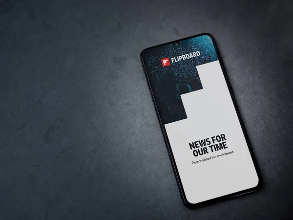 stock image Lod, Israel - July 8, 2020: Flipboard app launch screen with logo on the display of a black mobile smartphone on dark marble stone background. Top view flat lay with copy space.