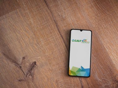 Lod, Israel - 8 Temmuz 2020: Clalit Sağlık Hizmetleri uygulama ekranı üzerinde siyah bir cep telefonunun ahşap arka planda sergilendiği logo. Üst görünüm düzlüğü kopyalama alanı ile yatıyordu.