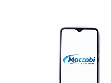 Lod, Israel - 8 Temmuz 2020: Maccbi Sağlık Hizmetleri uygulaması beyaz arkaplanda izole edilmiş siyah bir cep telefonunun logosu ile fırlatma ekranı. Üst görünüm düzlüğü kopyalama alanı ile yatıyordu.