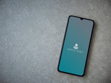 Lod, Israel - 8 Temmuz 2020: Seramik taş zemin üzerinde siyah bir cep telefonunun logosu olan Basit Alışkanlık uygulaması başlatma ekranı. Üst görünüm düzlüğü kopyalama alanı ile yatıyordu.