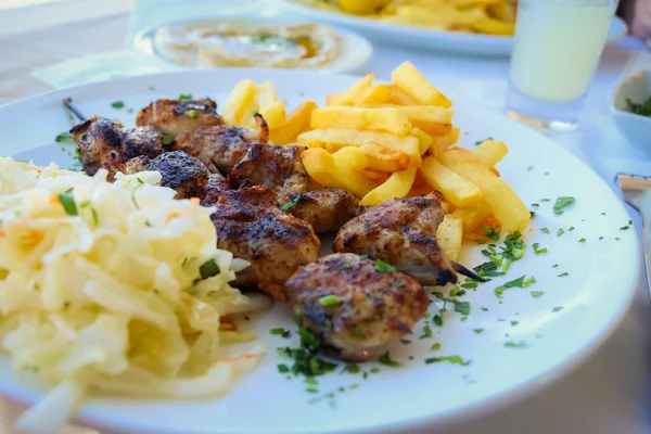 Grilled shashlik with french fries on plate