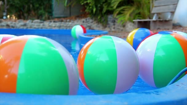 Bunte Strandbälle schweben in Zeitlupe im Pool — Stockvideo