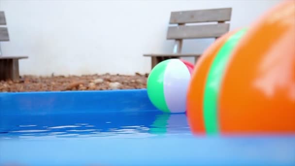 Coloridas bolas de playa flotando en la piscina en cámara lenta — Vídeos de Stock