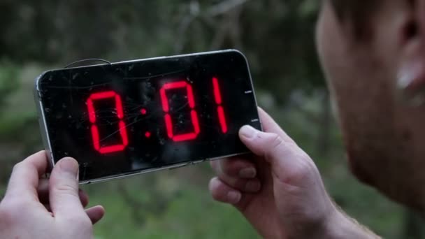 Man holding a broken digital clock and looking at that the time frozen on it — Stock Video