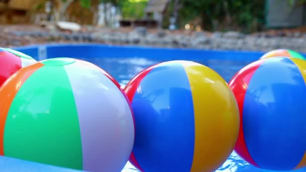 Kleurrijke strand ballen drijvend in zwembad — Stockvideo