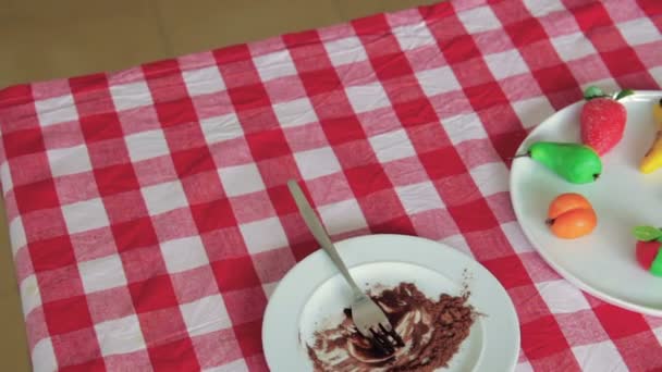 Los frutos de mazapán se colocan en un plato blanco sobre una mesa — Vídeo de stock