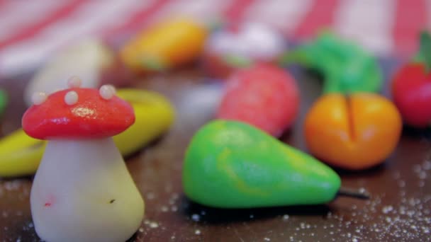 Les fruits de massepain sont placés sur une planche brune en bois sur une table — Video