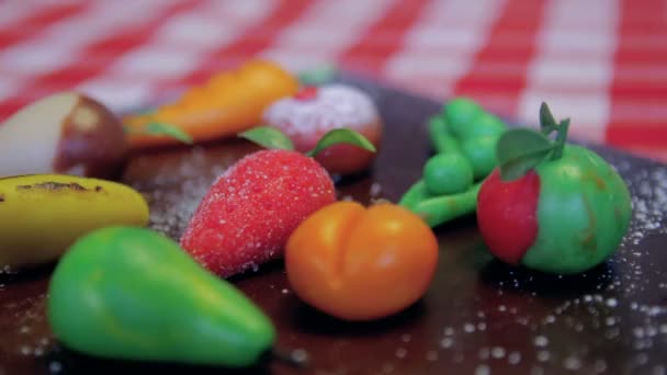 Марципановые фрукты помещаются на деревянную коричневую доску на столе — стоковое видео