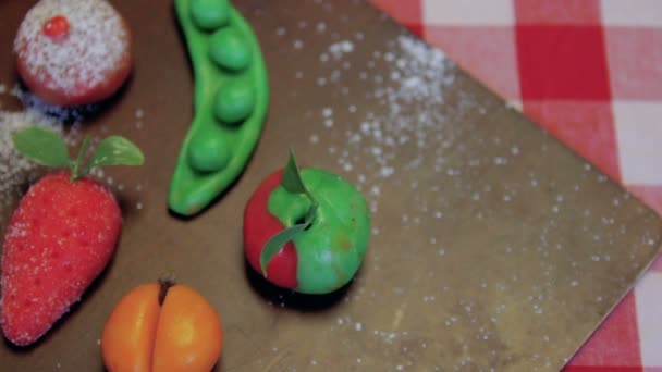 Les fruits de massepain sont placés sur une planche brune en bois sur une table — Video