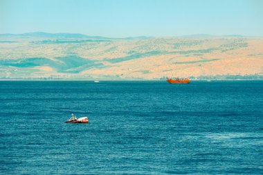Brown wooden boat sailing in Sea of Galilee clipart