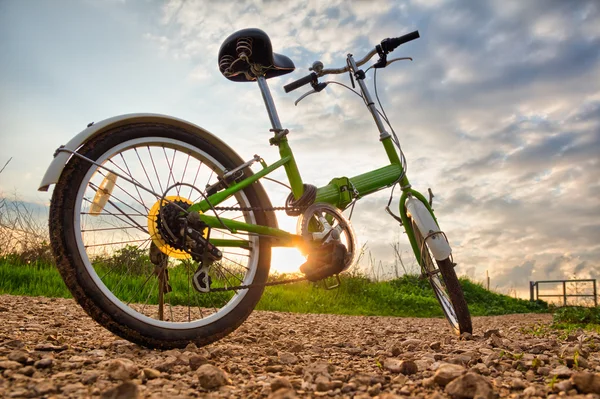 Bicicletas estacionadas em uma estrada de terra durante o pôr do sol — Fotografia de Stock