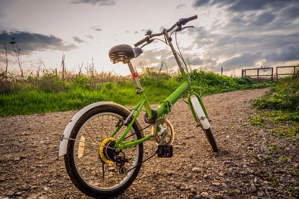 Bicicletas estacionadas em uma estrada de terra durante o pôr do sol — Fotografia de Stock