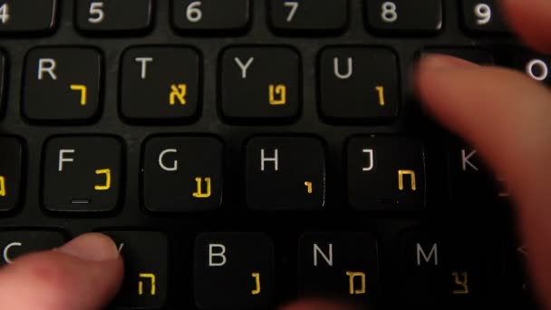 Hombre escribiendo en un teclado con letras en hebreo e inglés — Vídeo de stock