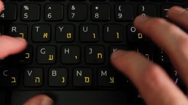 Adam bir klavye İngilizce ve İbranice harflerle yazarak