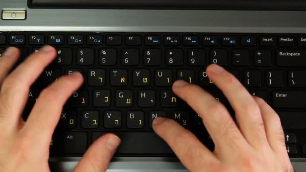 Hombre escribiendo en un teclado con letras en hebreo e inglés — Vídeo de stock