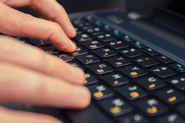 Man typing on a keyboard with letters in Hebrew and English