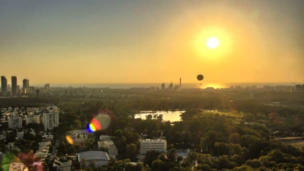 Aerial view of Tel Aviv skyline at sunset - silhouette of buildings, a hot air balloon flying in the sky and boats in the lake in Hayarkon Park. 4K Timelapse. — Stock Video