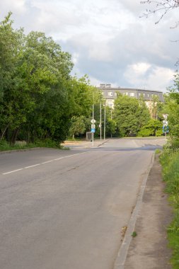 Sakin bir sokakta park ağaçlarıyla çevrili 