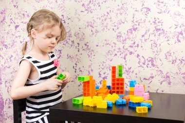 küçük kız masada tuğla oluşturur