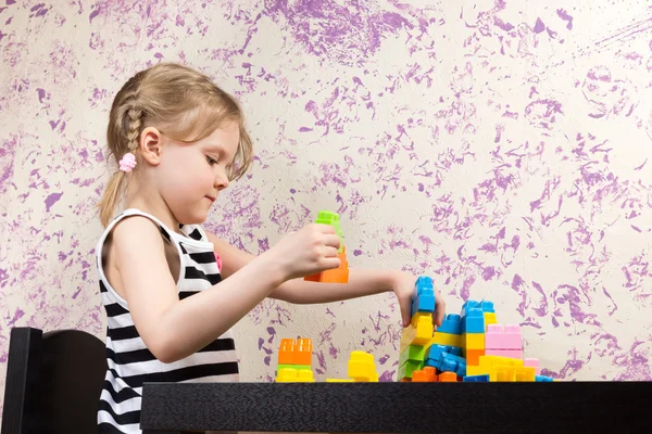 Маленькая девочка строит кирпичи за столом — стоковое фото