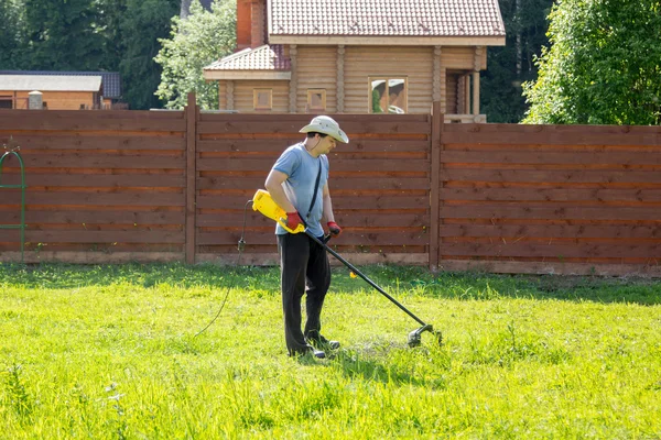 man mows the grass with string trimmer