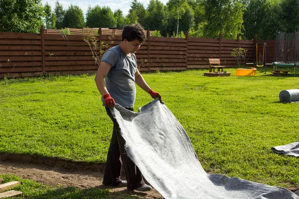 Mężczyzna leżał geotekstyliów w pit dla ścieżki ogrodowe — Zdjęcie stockowe