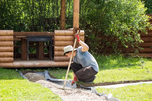 man evens gravel on path with rake