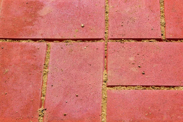 red concrete paving slabs with sand closeup