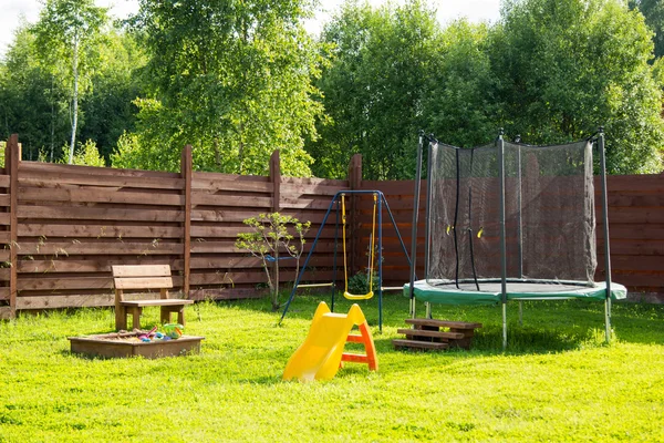 Parco giochi per bambini con trampolino e altalene — Foto Stock