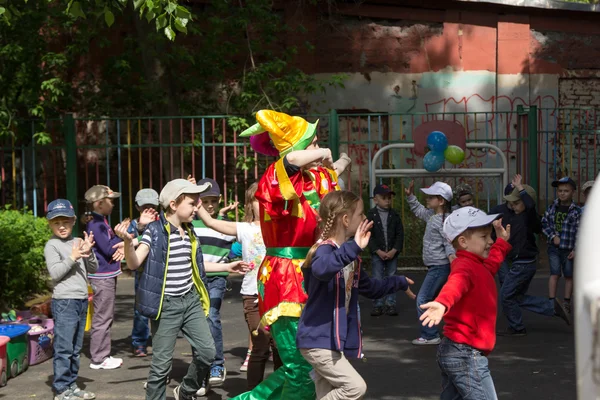 Předškolní pedagog zabavit děti v oblecích šašci v — Stock fotografie