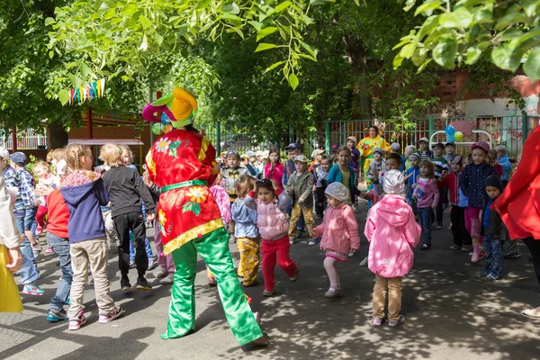 Předškolní pedagog zabavit děti v oblecích šašci v — Stock fotografie