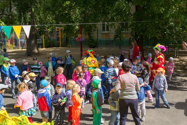 Maestro de preescolar entretener a los niños en trajes de bufones en el — Foto de Stock
