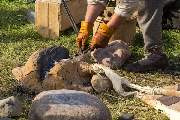 Smith pulls a nail out of fire tongs — Stock Photo, Image