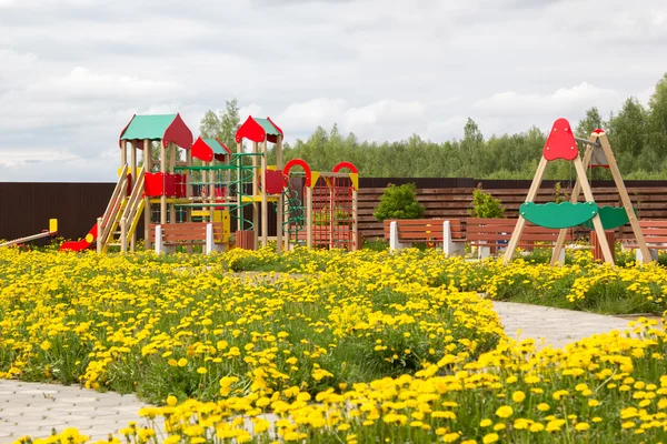 Children playground among blossoming dandelions — Stock Photo, Image
