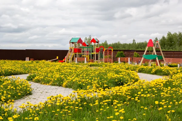 Children playground among blossoming dandelions — Stock Photo, Image