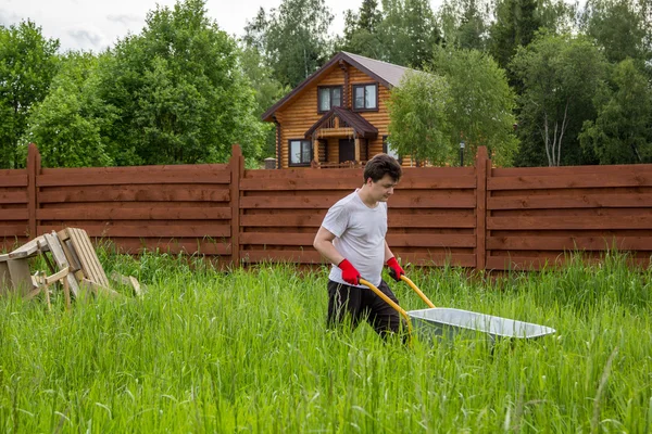 Mężczyzna niesie ze sobą taczki przez gąszcz trawy — Zdjęcie stockowe