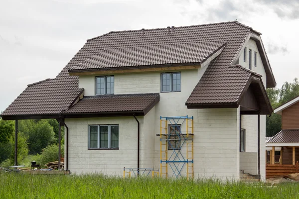 Nedokončené kamenný dům s lešení proti zdi — Stock fotografie