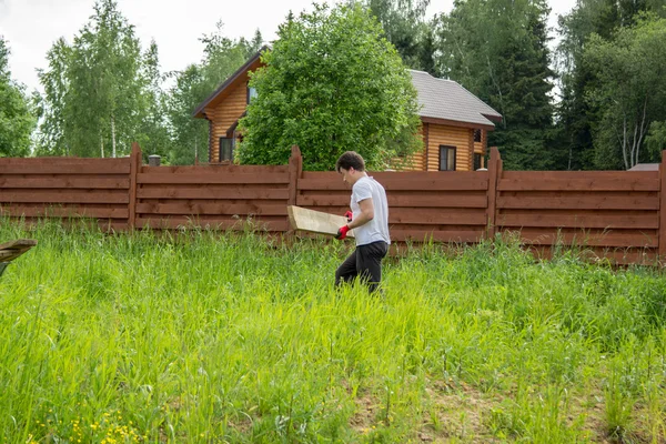 Man carries a wooden board in grass — Stock Photo, Image